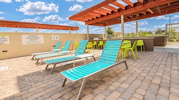 An outdoor pool area with lounge chairs and a barbecue setup.