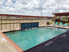 Una piscina al aire libre, sillones reclinables de piscina
