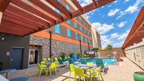 A hotel patio with outdoor seating, a swimming pool, and a stone wall.