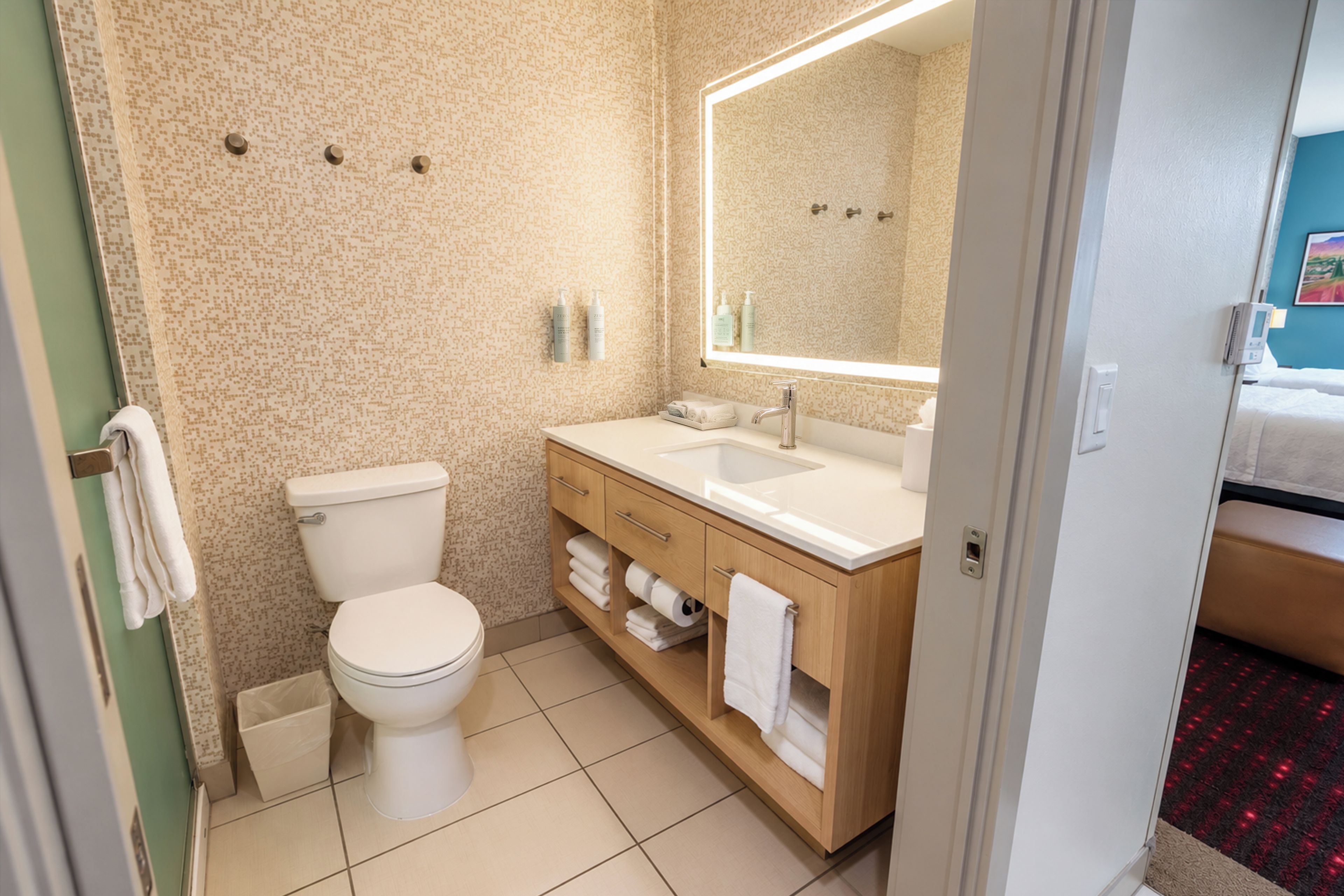A bathroom with a toilet, sink, and mirror.
