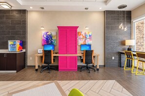 A modern office space with two desks, chairs, and artwork on the walls.