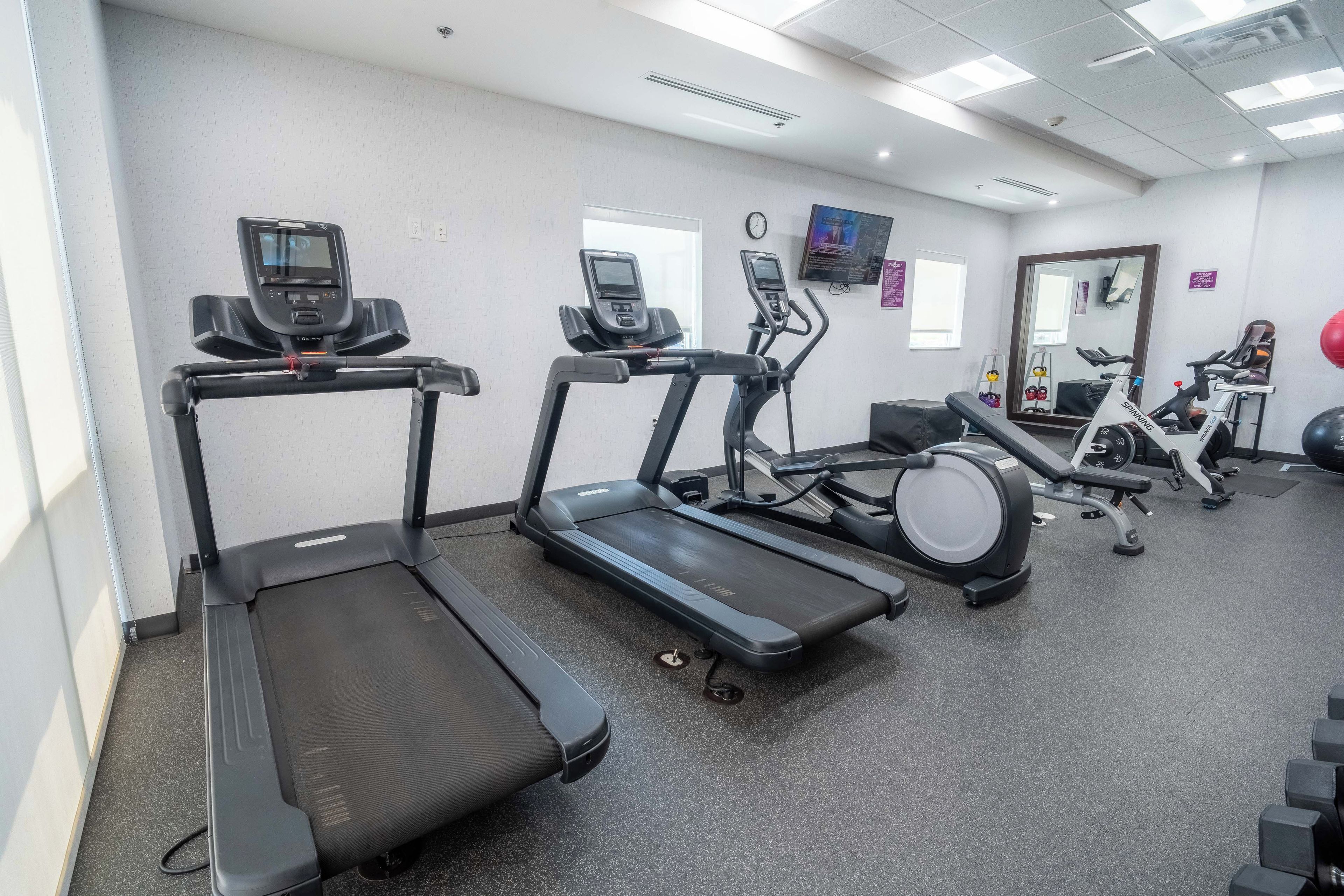 Un gimnasio con cintas de correr, elípticas y una bicicleta de spinning.