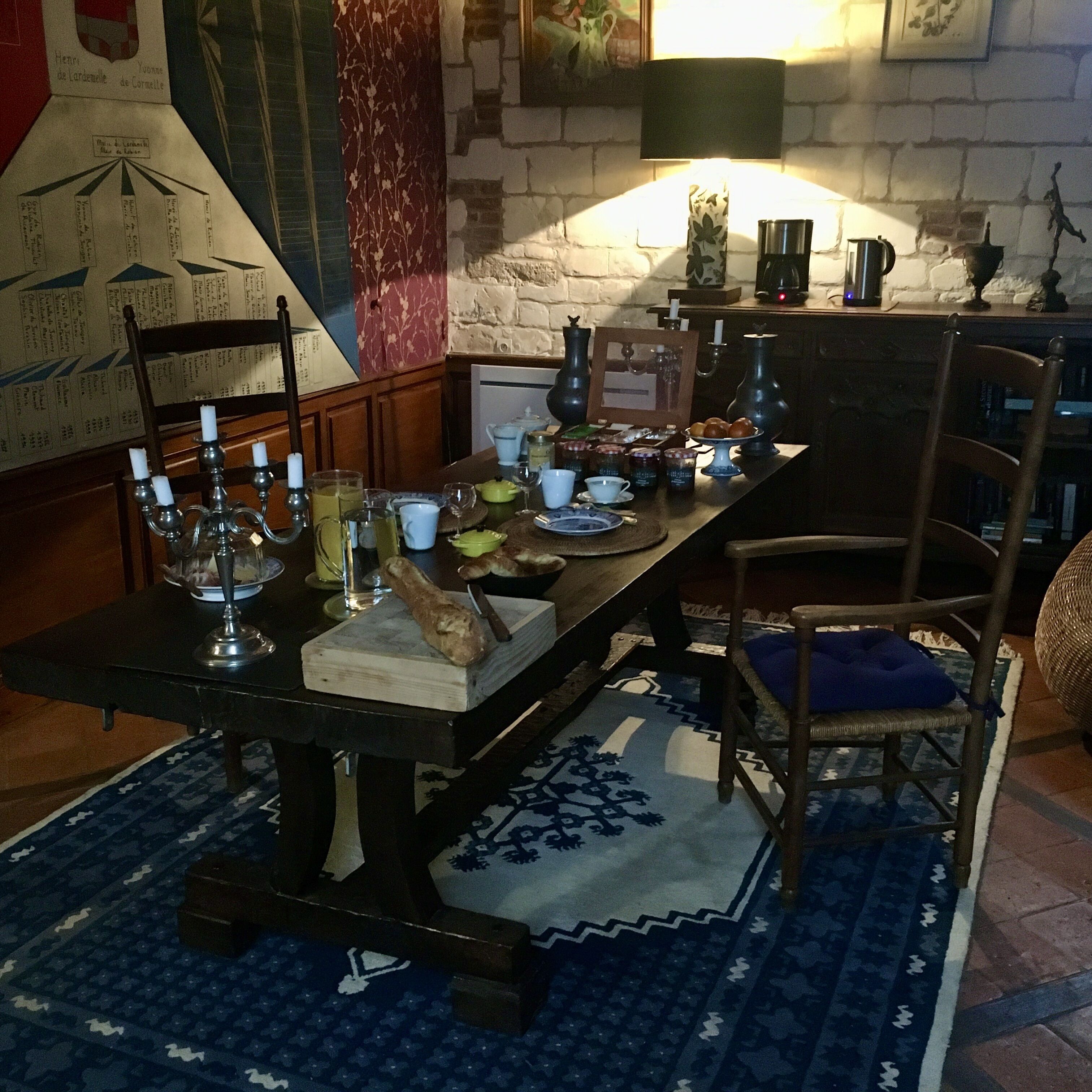 A dining table set with candles, plates, and a bread loaf.