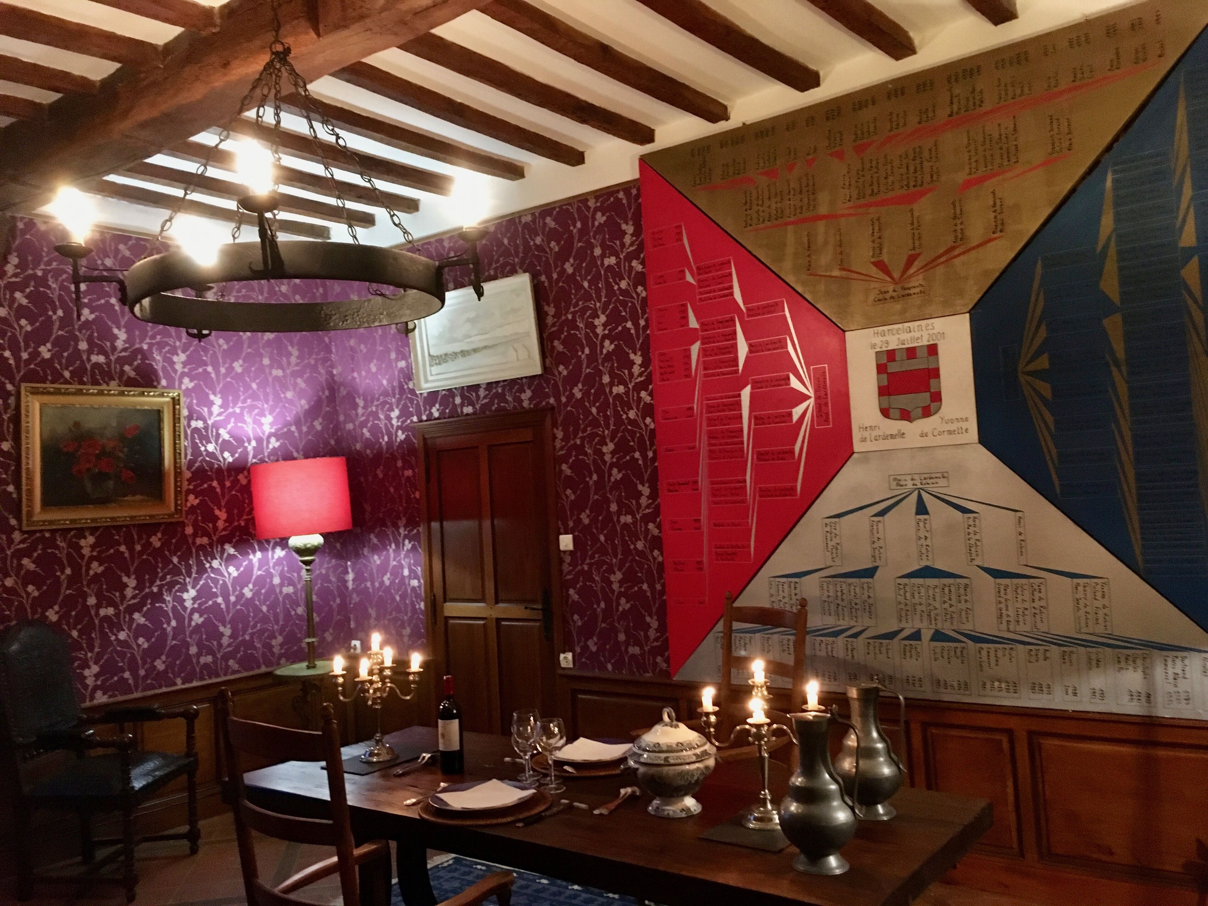 Un coin repas avec une table dressée pour deux personnes, des bougies et une grande carte géographique accrochée au mur.