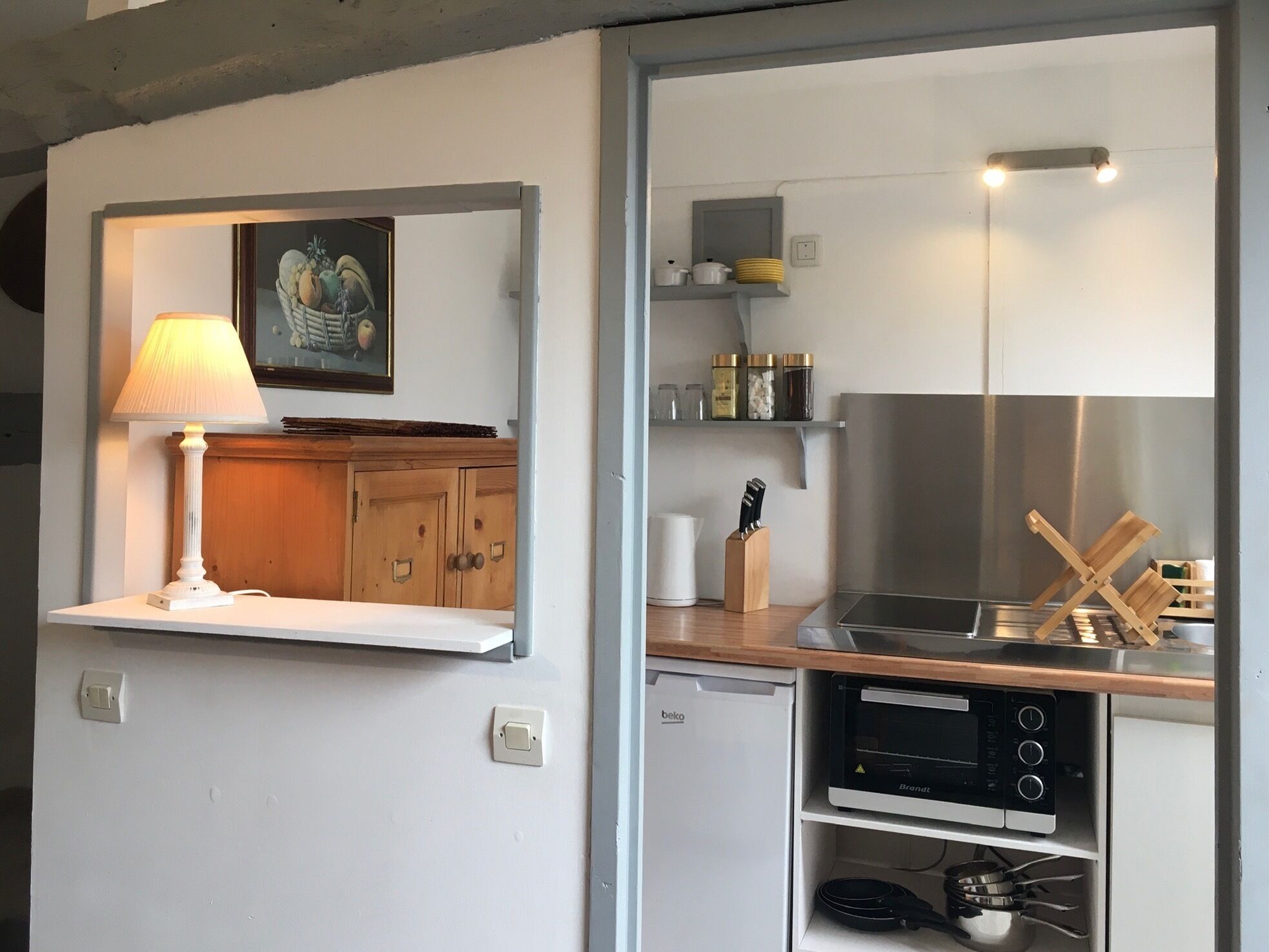 Una cocina compacta con horno integrado, un lavamanos y una encimera con un juego de cuchillos.