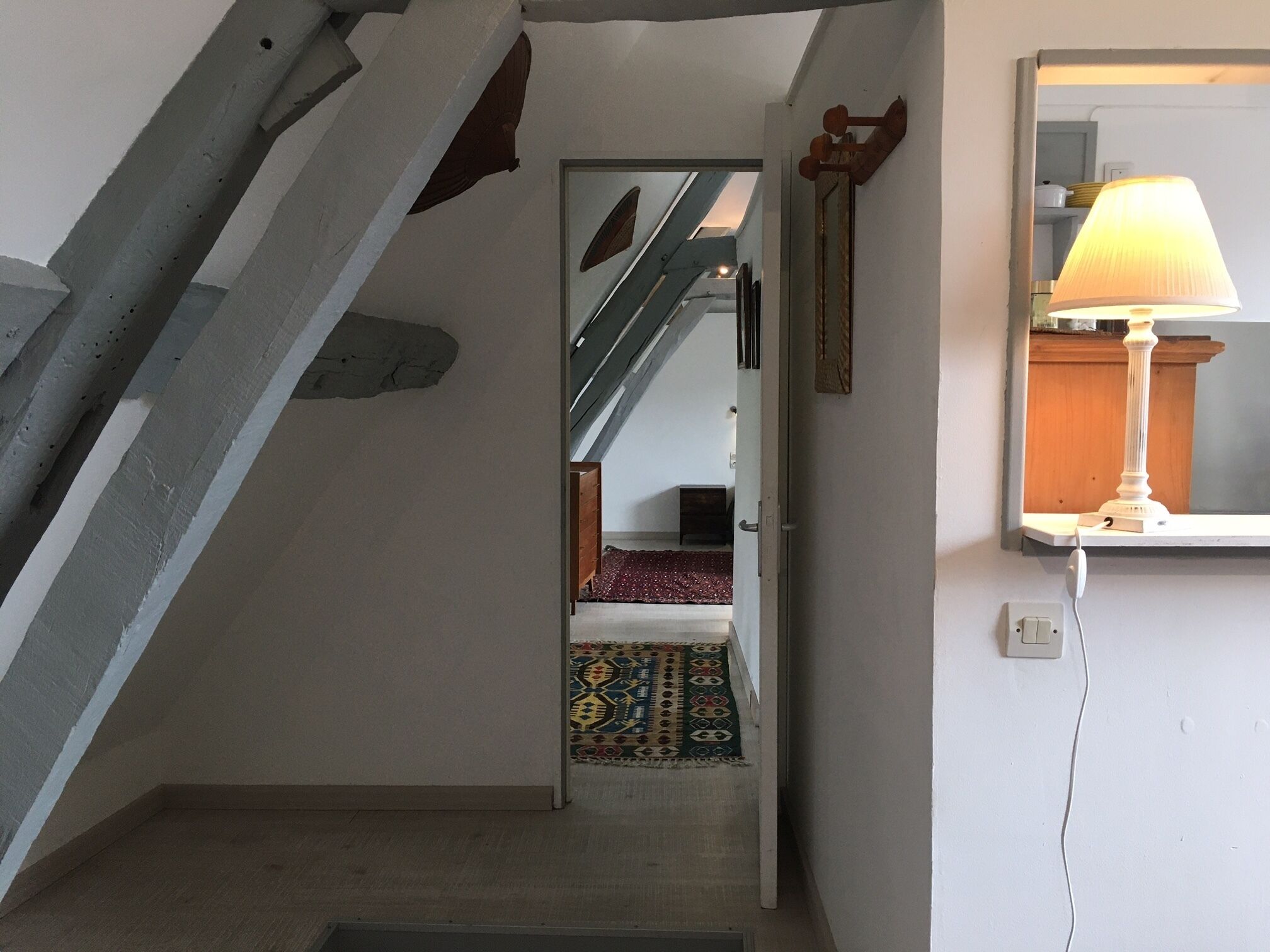Un escalier menant à une chambre à coucher où se trouvent un lit et un tapis à motifs.