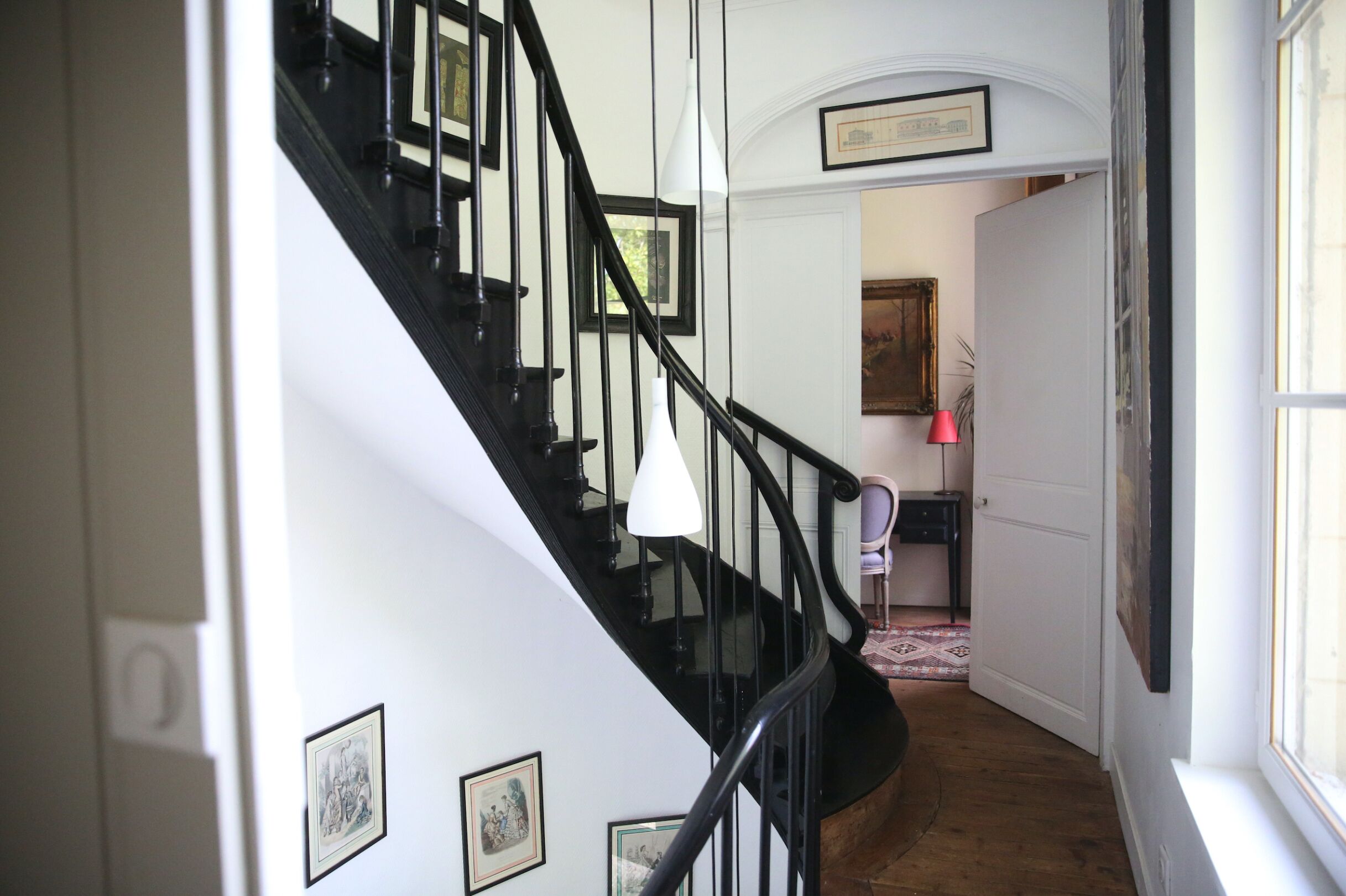 A staircase with black railings, white walls, and framed pictures.