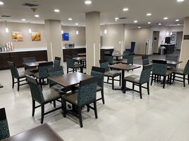 A spacious dining area with multiple tables and chairs, a kitchen area in the background, and a sign indicating room number 36.