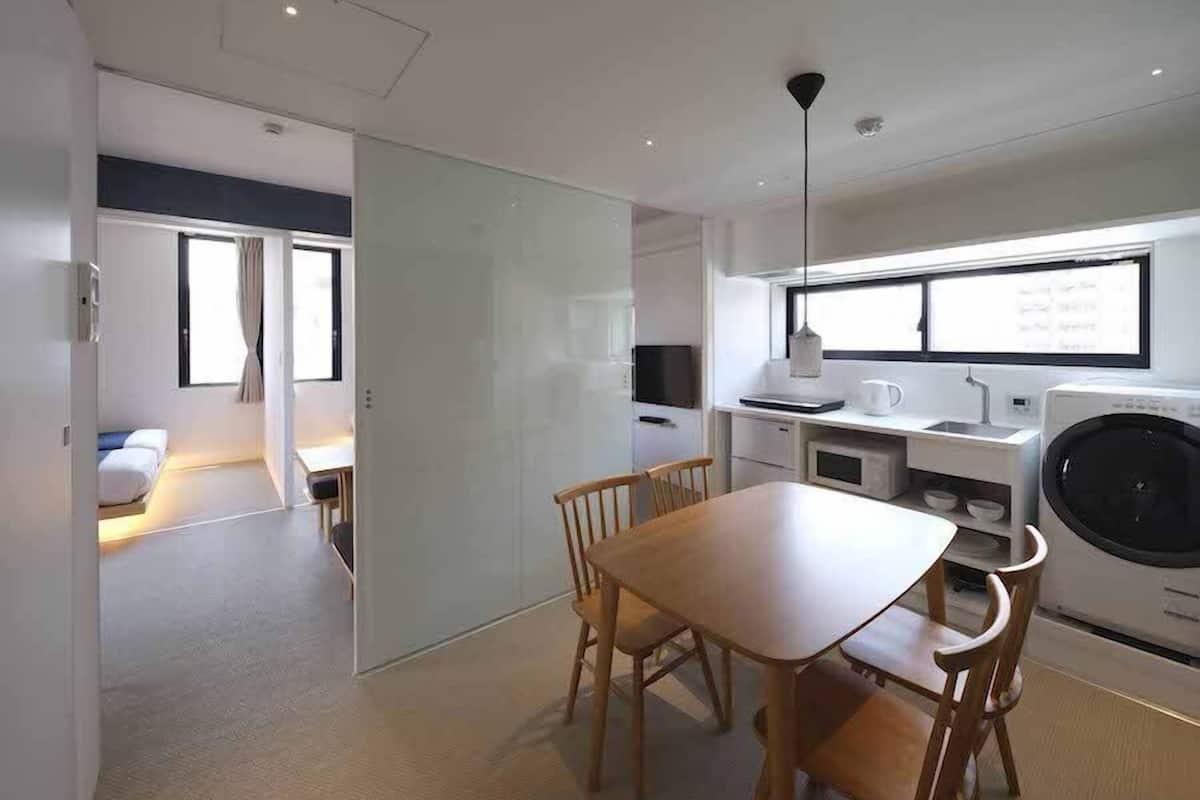 Una cocina compacta y moderna con comedor, lavadora y televisor.