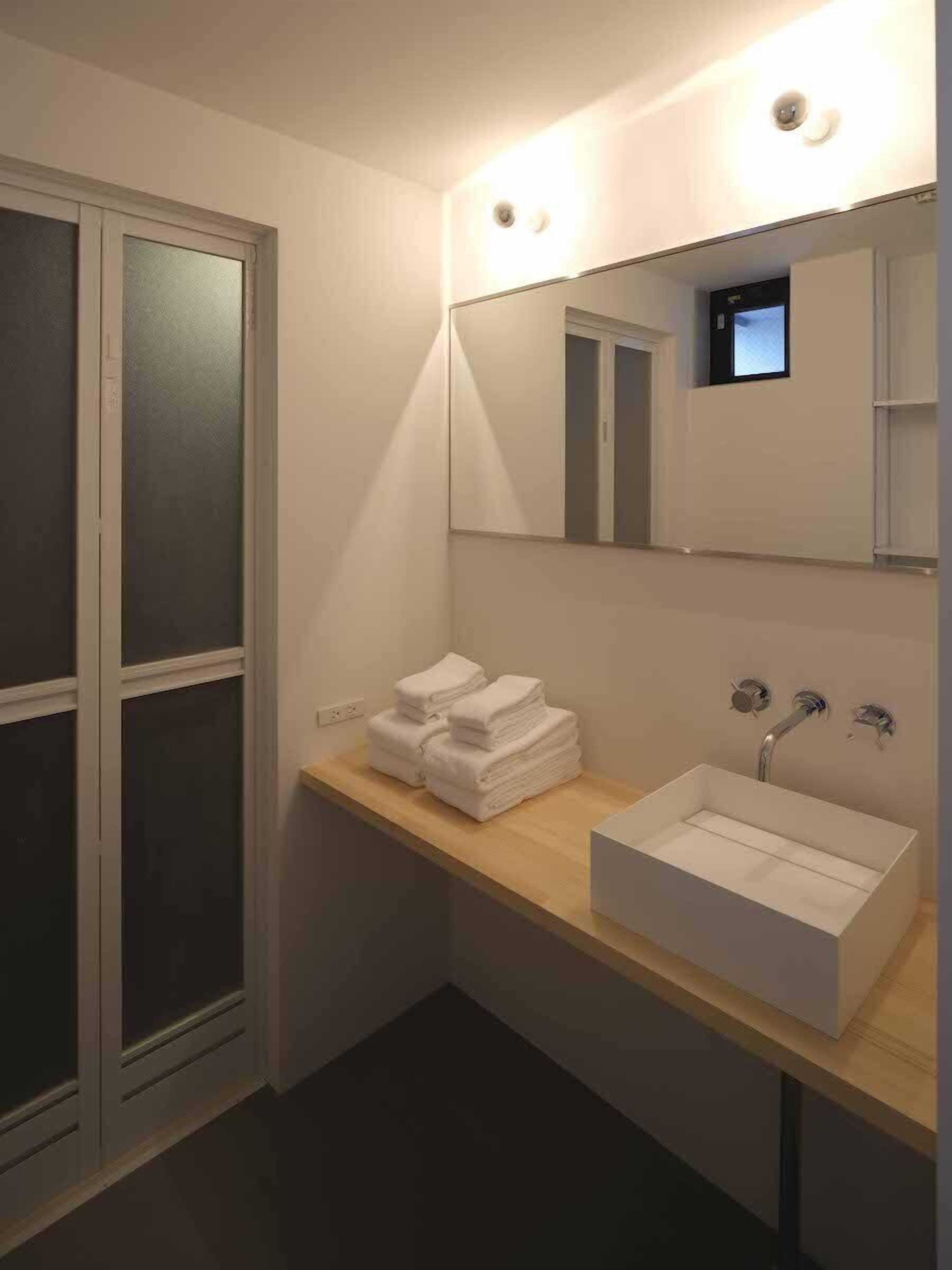 A modern bathroom with a large mirror, a sink, and a towel rack.