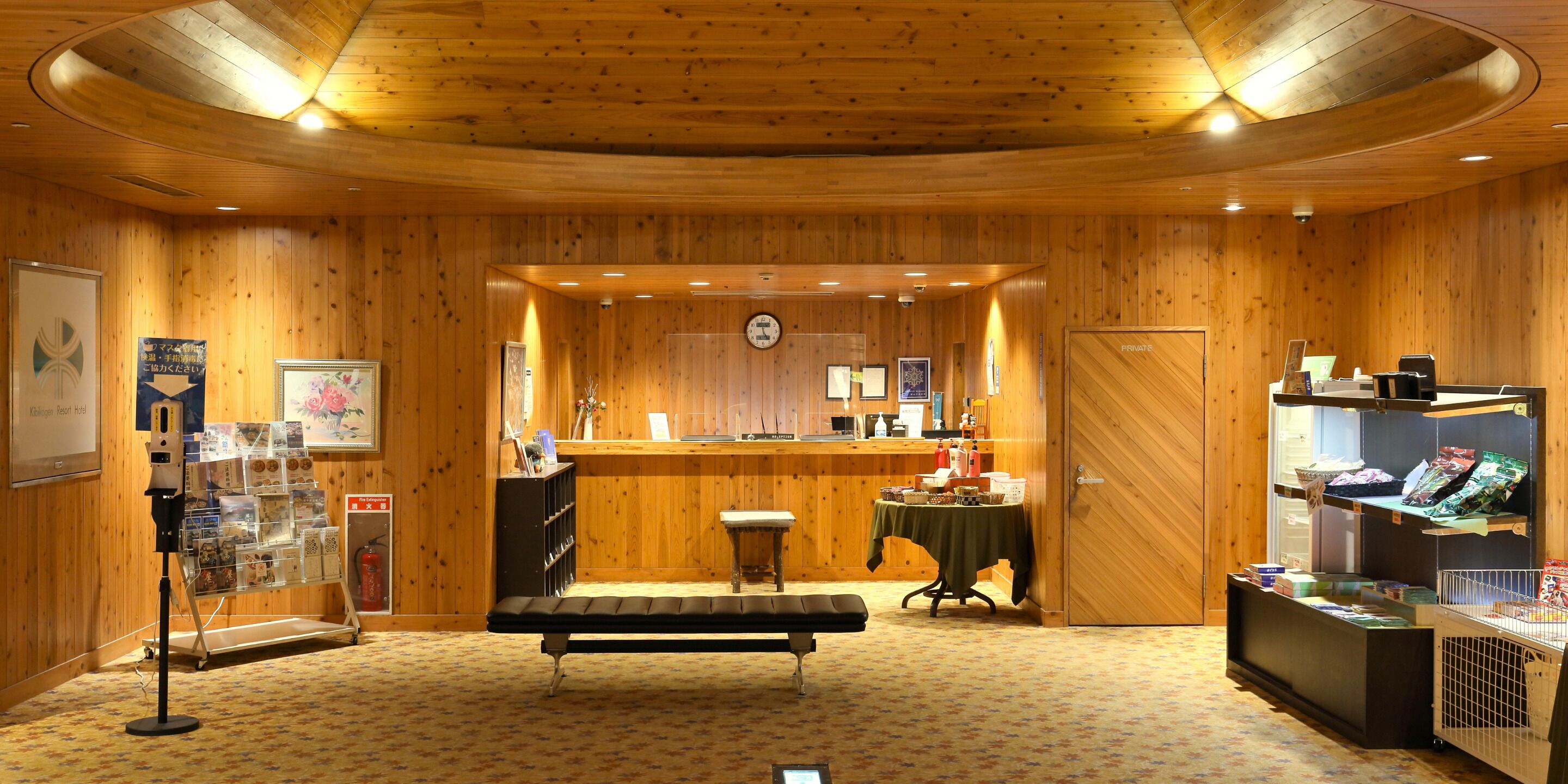 A wooden interior with a reception desk, a bench, and a display of items.