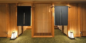 A traditional Japanese room with tatami flooring, sliding doors, and two wall-mounted lanterns.