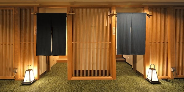 A traditional Japanese room with tatami flooring, sliding doors, and two wall-mounted lanterns.