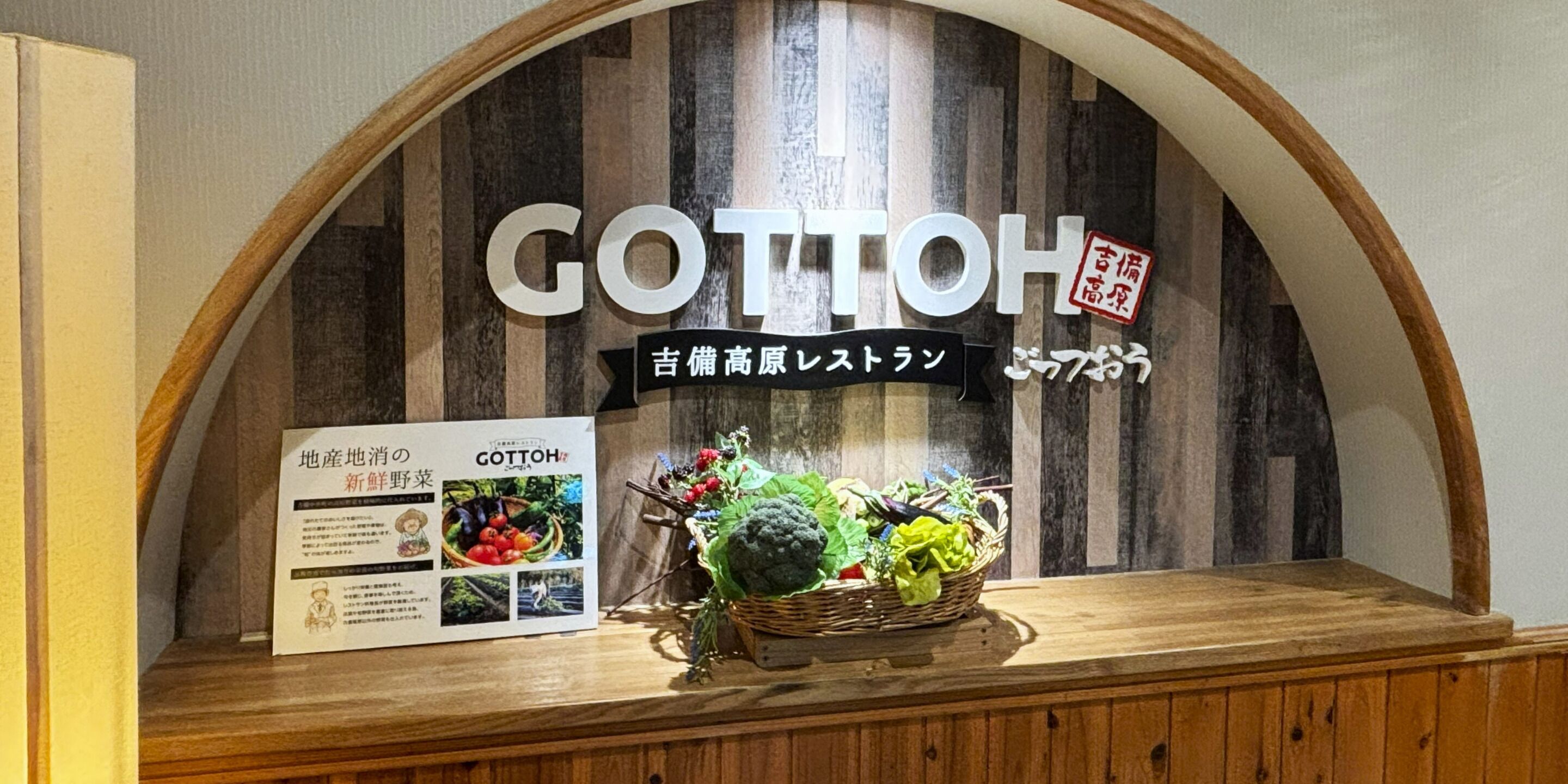 A wooden counter with a sign reading 'GOTTOH' and a basket of vegetables.