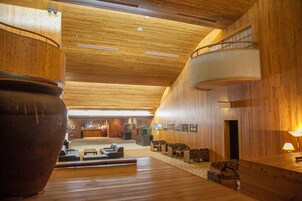 Un interior de madera con una mesa de recepción, zona de estar y un jarrón grande.