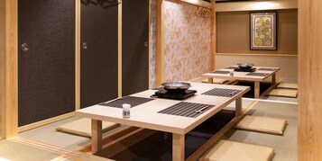 Una habitación japonesa tradicional con esteras de tatami, mesas bajas y puertas correderas shoji.