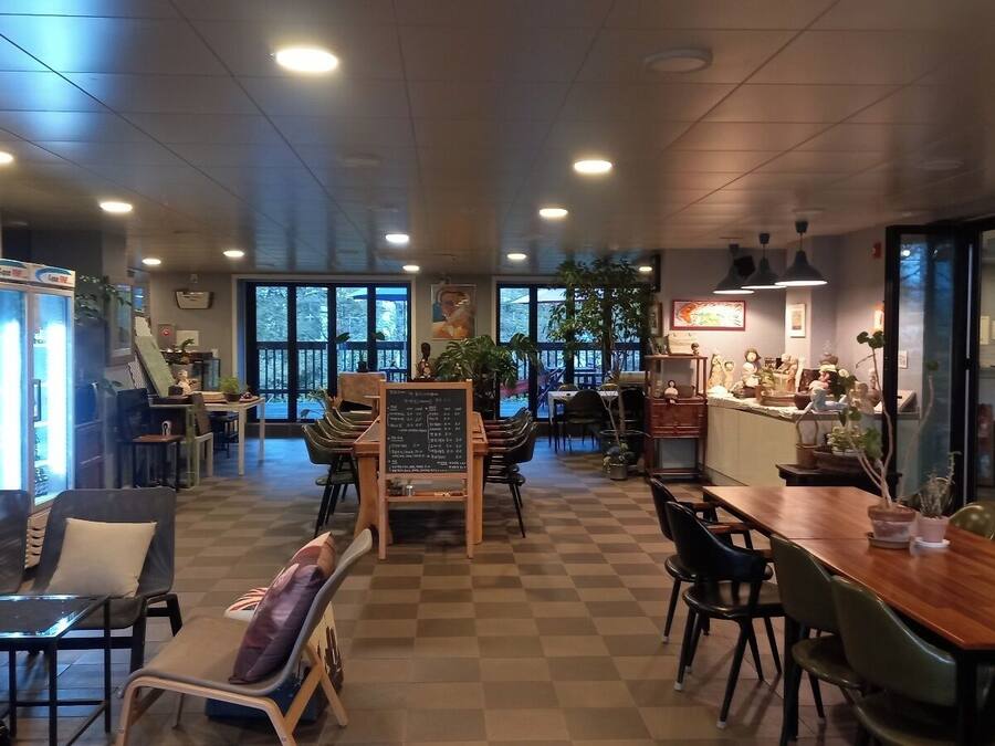 Un café amplio con suelo a cuadros, mesas de madera y asientos cómodos.
