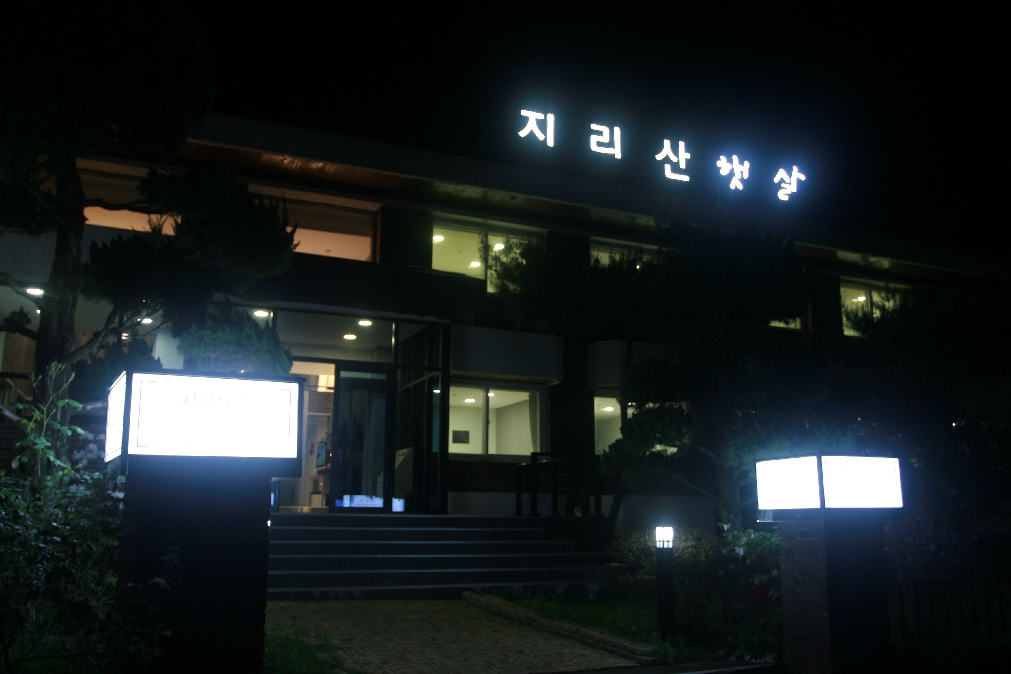 A building with a sign that reads "Ji-ri san ak" in Korean, surrounded by well-lit areas and steps leading to the entrance.