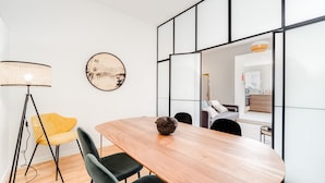 A modern dining area with a wooden table, black chairs, a yellow chair, a floor lamp, and a decorative pine cone centerpiece. - Nomad's By Sta Catarina Flats - 3BDR Family (Porto)