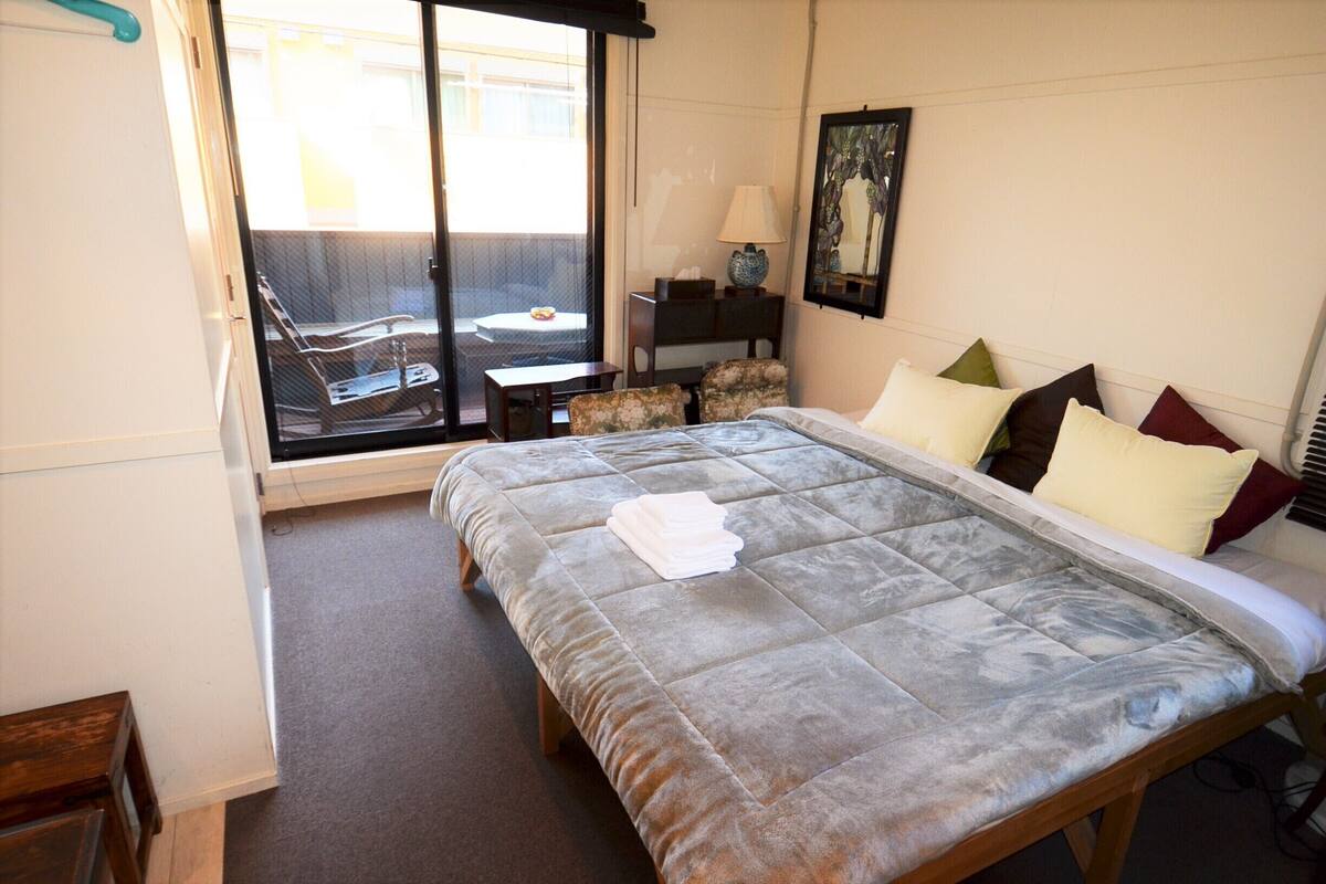 Ein Hotelzimmer mit einem Bett, einem Sessel, einem Tisch und Blick ins Freie.