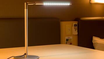 A hotel room with a bedside table, a lamp, a telephone, and a wall-mounted light fixture.