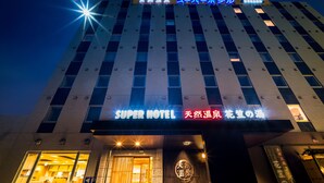 Ein Hotel mit einem Schild, das „Super Hotel“ zeigt, und einem großen, beleuchteten Eingang.
