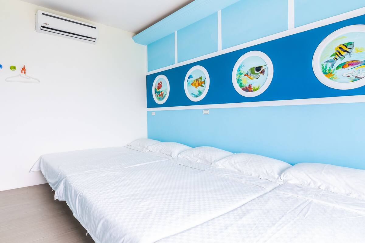 A bedroom with a bed, white bedding, a blue accent wall, and four circular wall decorations.