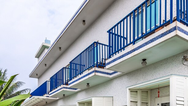 Un immeuble de deux étages avec des murs extérieurs blancs et des balustrades bleues sur les balcons.