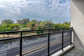 A balcony with a view of a road and trees.