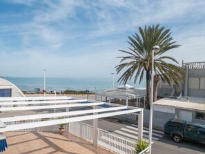 A hotel with a view of the sea, a palm tree, and a covered outdoor area.