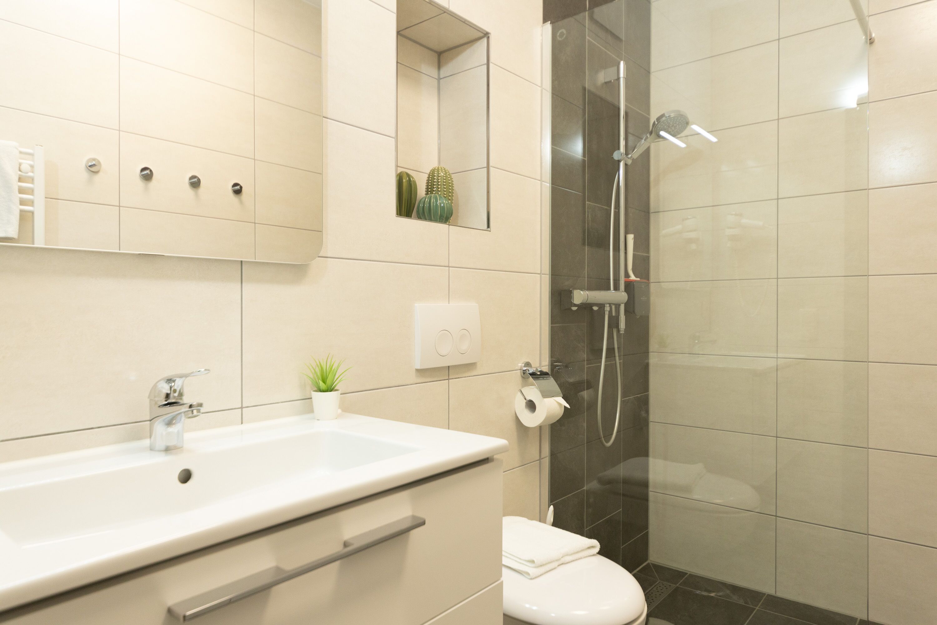 Een moderne badkamer met een grote wastafel, toilet en douche.