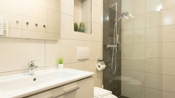 Een moderne badkamer met een grote wastafel, toilet en douche.