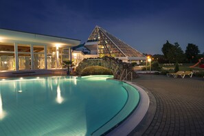 A swimming pool with a glass pyramid structure in the background.