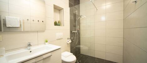 A modern bathroom with a white sink, toilet, and shower.