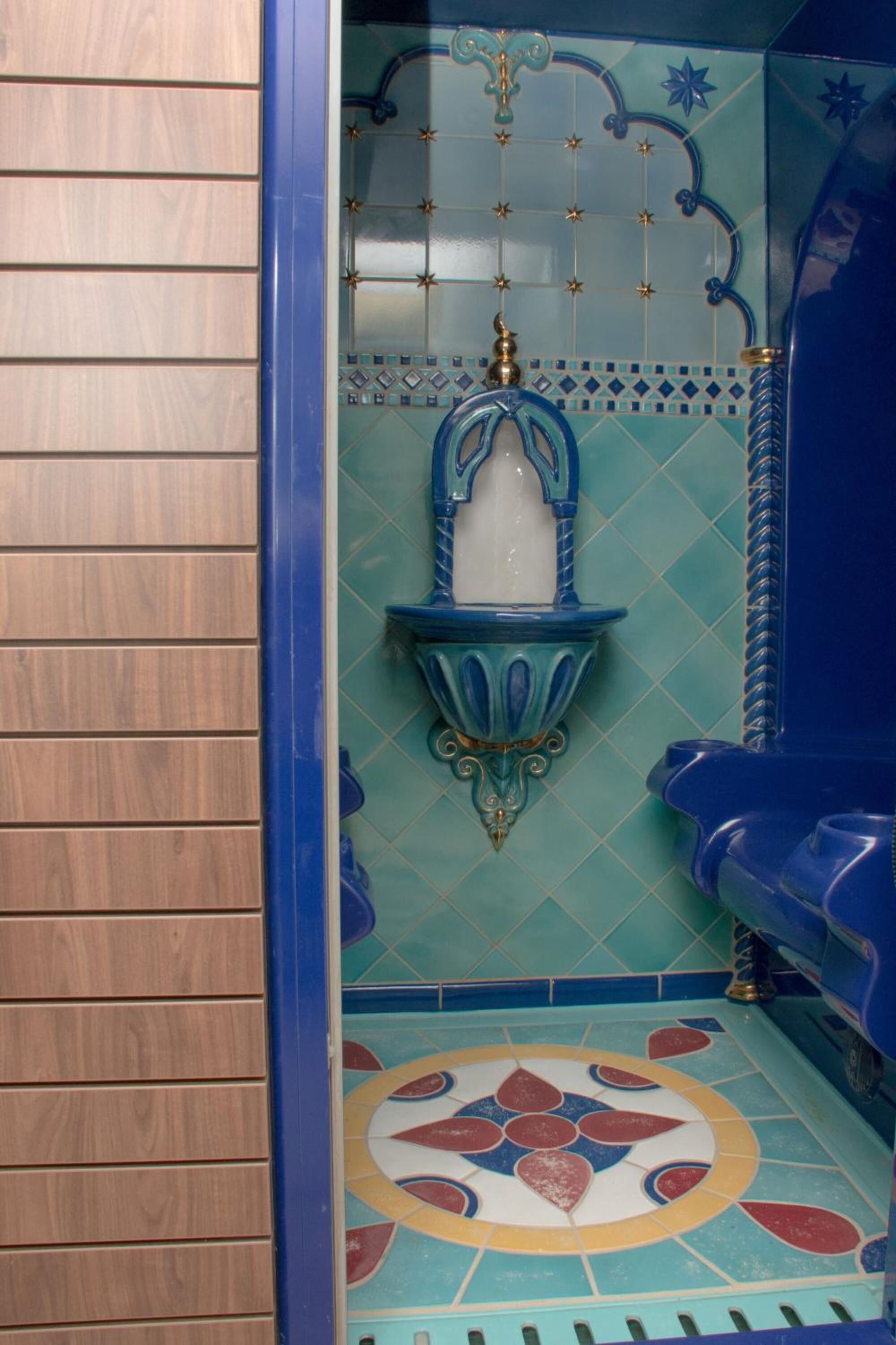 Ein Badezimmer mit einer blauen Badewanne, einer dekorativen Wandleuchte und einem gemusterten Boden.