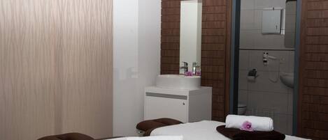 Une salle de spa équipée de deux tables de massage, d’un lavabo blanc et d’un miroir.