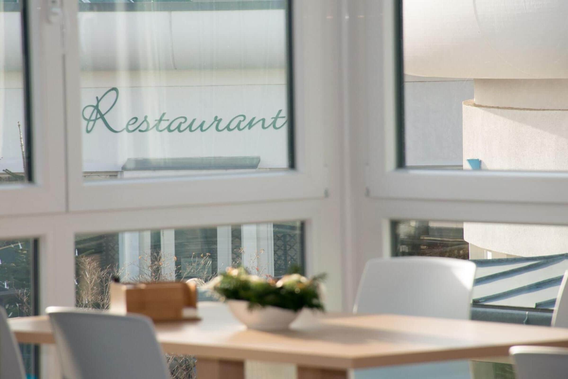 A restaurant interior with a table, chairs, and a window with the word "Restaurant" visible.