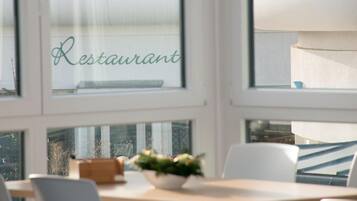 A restaurant interior with a table, chairs, and a window with the word "Restaurant" visible.