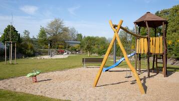 Un parque infantil con columpios, tobogán y estructura para escalar.