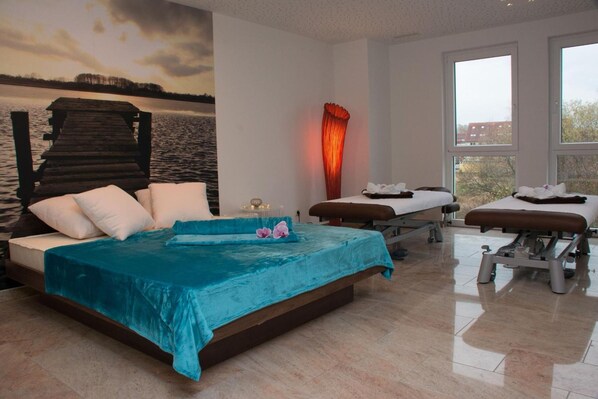 Un dormitorio con una cama, una camilla de masaje y vista a un cuerpo de agua.