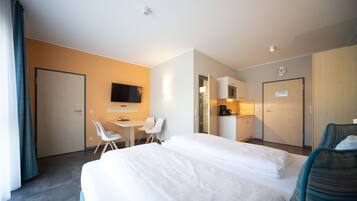 Een hotelkamer met een groot bed, een bureau met stoelen, een televisie en een kitchenette.