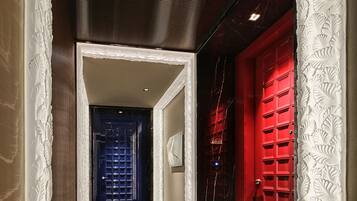A hallway with a patterned wall, a red door, and a blue door at the end.