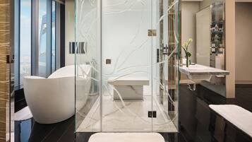 Un baño moderno con ducha envuelta en cristal, una bañera independiente y un tocador con espejo.