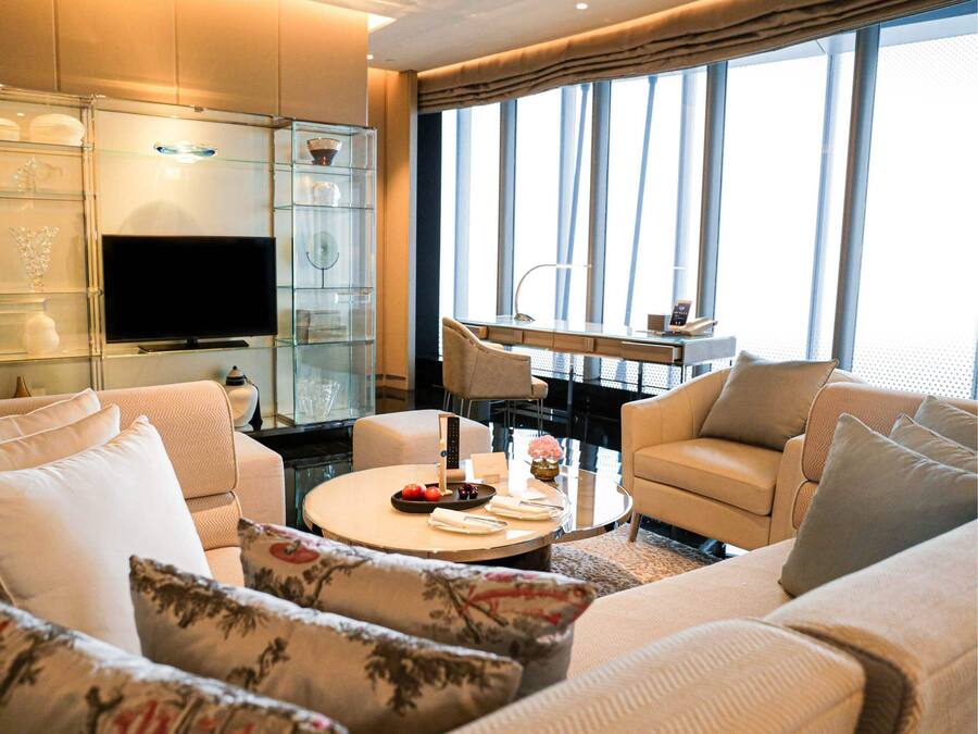 Ein modernes Wohnzimmer mit einer Couch, Sesseln, einem Couchtisch, einem Fernseher und einer Vitrine mit Dekoration.