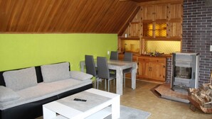 Una sala acogedora con sofá, mesa de comedor, sillas y chimenea.