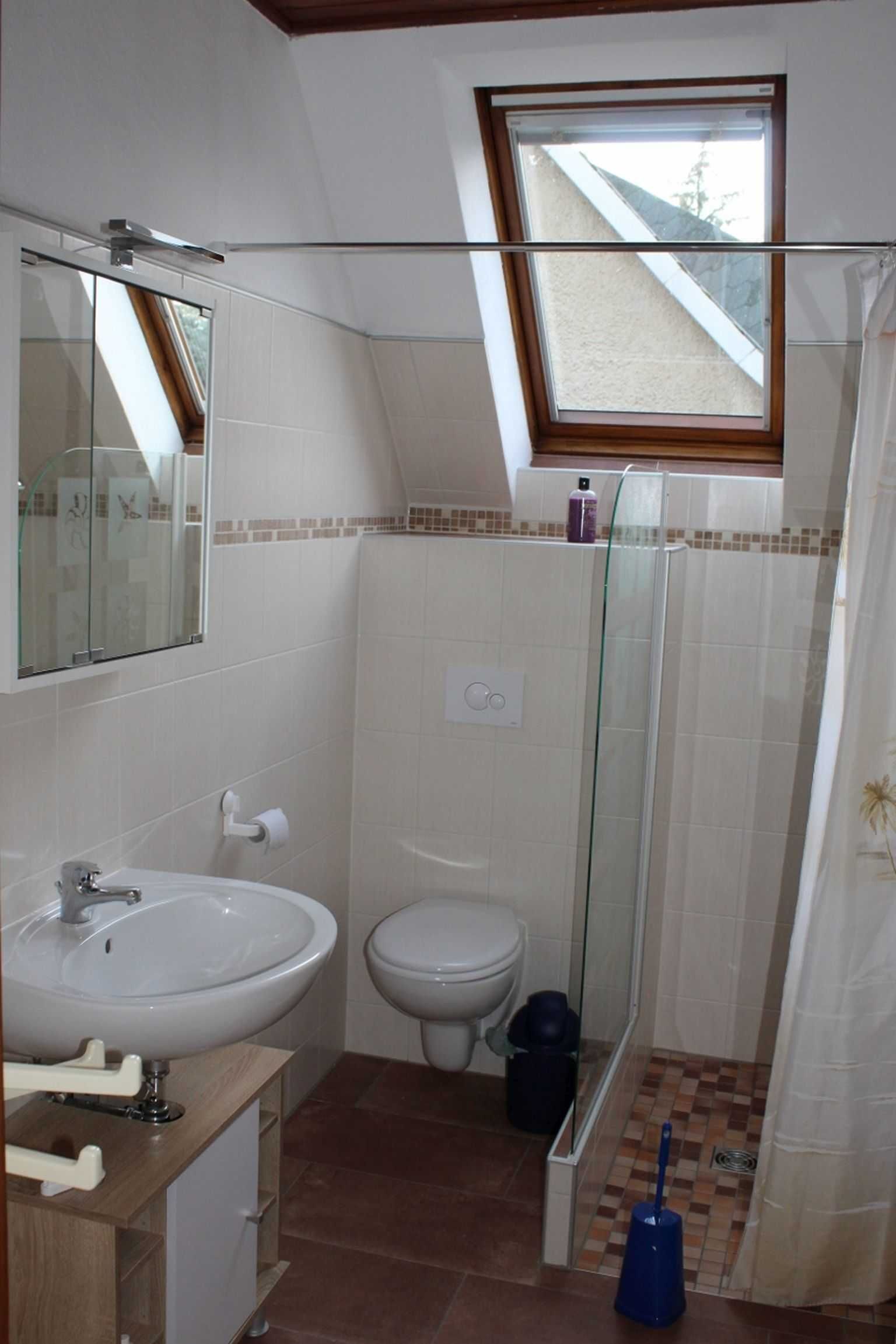 A compact bathroom with a white sink, toilet, and glass shower enclosure.