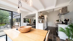 Eine moderne Küche mit einem großen Holztisch, weißen Schränken und Blick ins Freie.