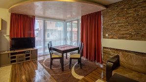 Una sala de estar con televisor, una mesa de comedor y una pared de piedra.