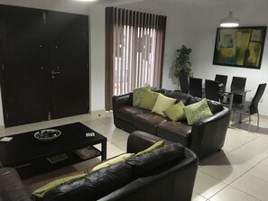 A living room with a sofa, coffee table, and a dining area with chairs and a table.