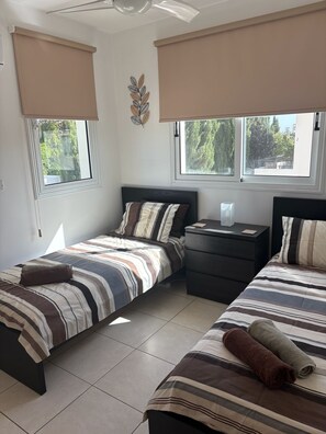 A bedroom with two beds, a nightstand, and a decorative wall piece. - Luxury Villa - Private Pool and Wifi Perfect Location for a Holiday! (Paralimni)